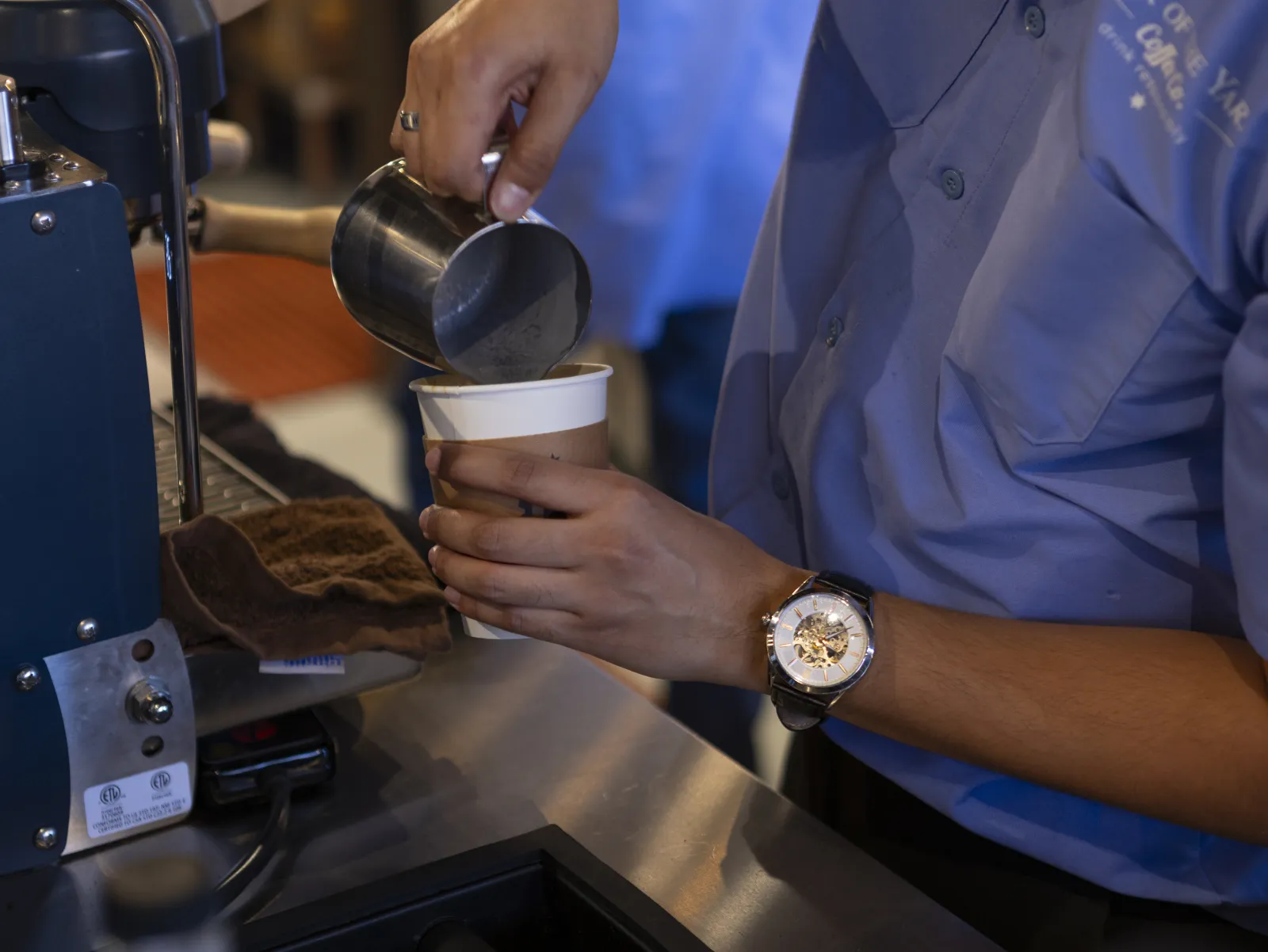 Barista vertiendo leche vaporizada en un vaso de Back of the Yards