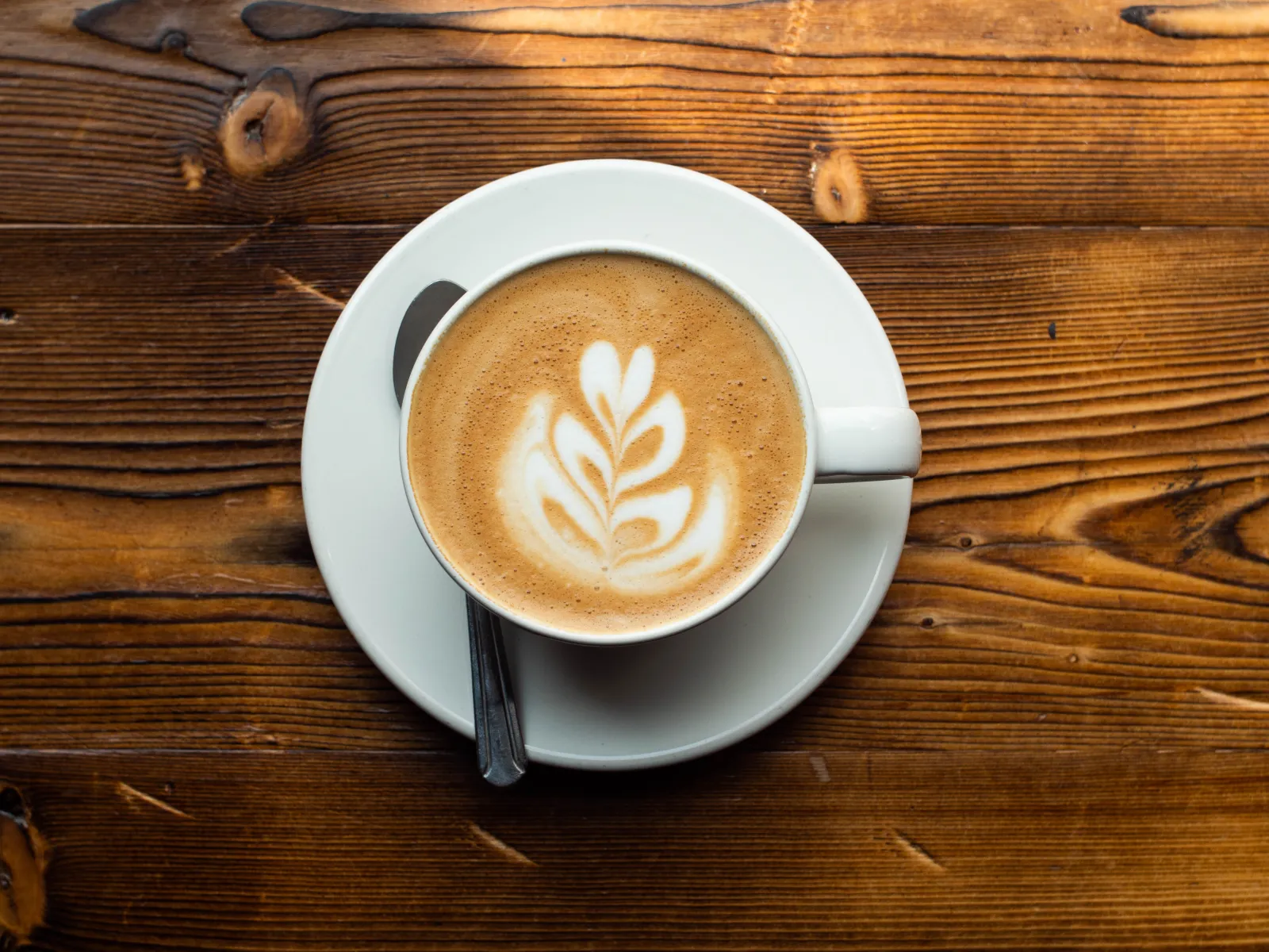 Latte con arte de roseta visto desde arriba sobre una mesa de madera